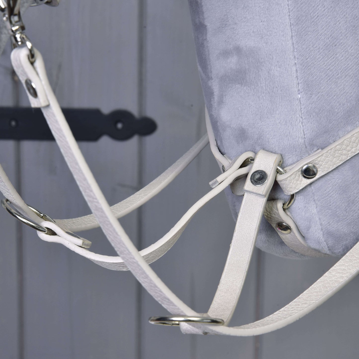 Detail světle šedého Hobby Horse s koženkovým setem Aqua - uzdečka, otěže a martingal od Hobby Horse LarDen, s kovovými přezkami na světle šedém dřevěném pozadí – ideální pro nadšence.