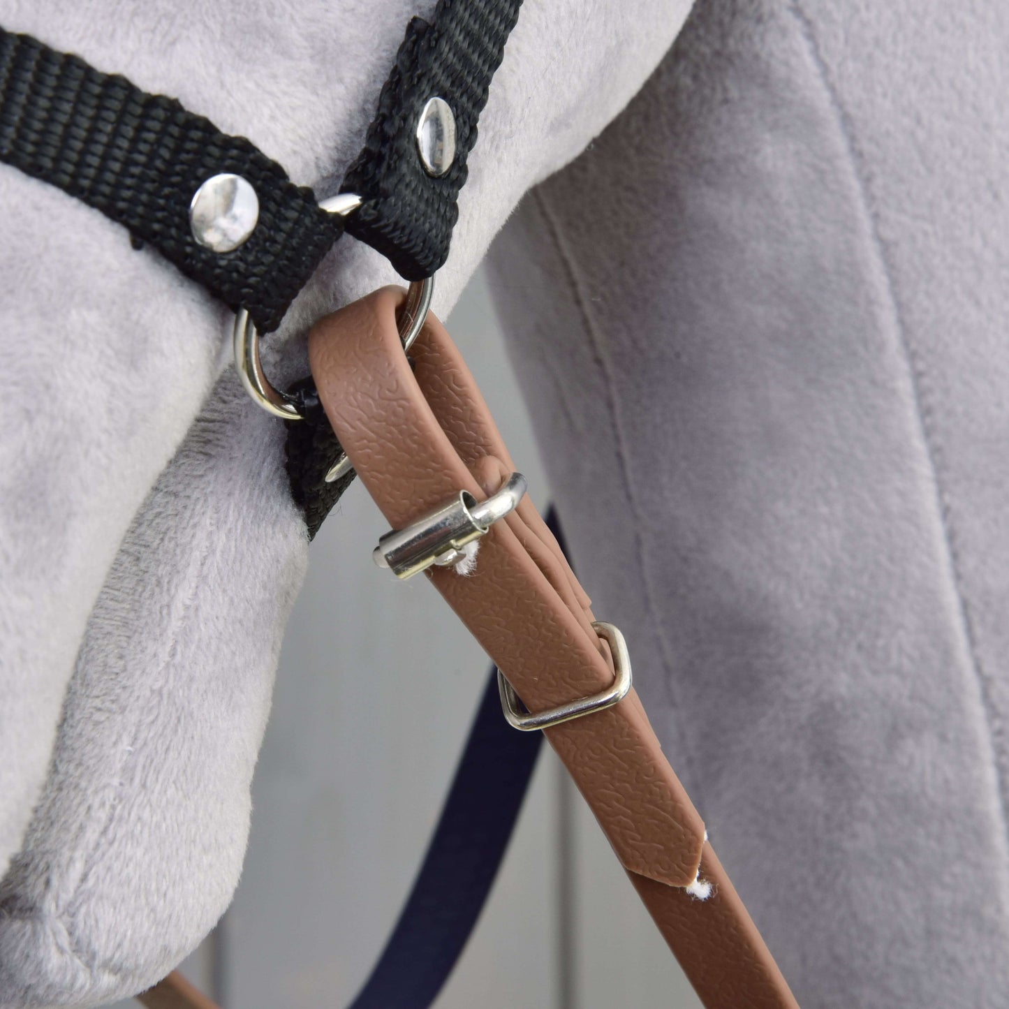 Detail měkké světle šedé plyšové hračky s Otěžemi pogumovanými Brown Purple od Hobby Horse LarDen – bezudidlovou uzdečkou s černými řemínky, kovovými kroužky a hnědým páskem z umělé kůže.