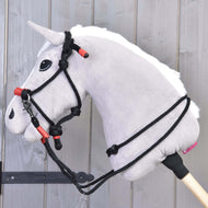 Hlava šedého plyšového Hobby Horse s černou uzdečkou, červenými akcenty a Hobby Horse LarDen Provazový set Spark, připevněná na dřevěné tyči, zobrazená na pozadí ze světlých dřevěných panelů.