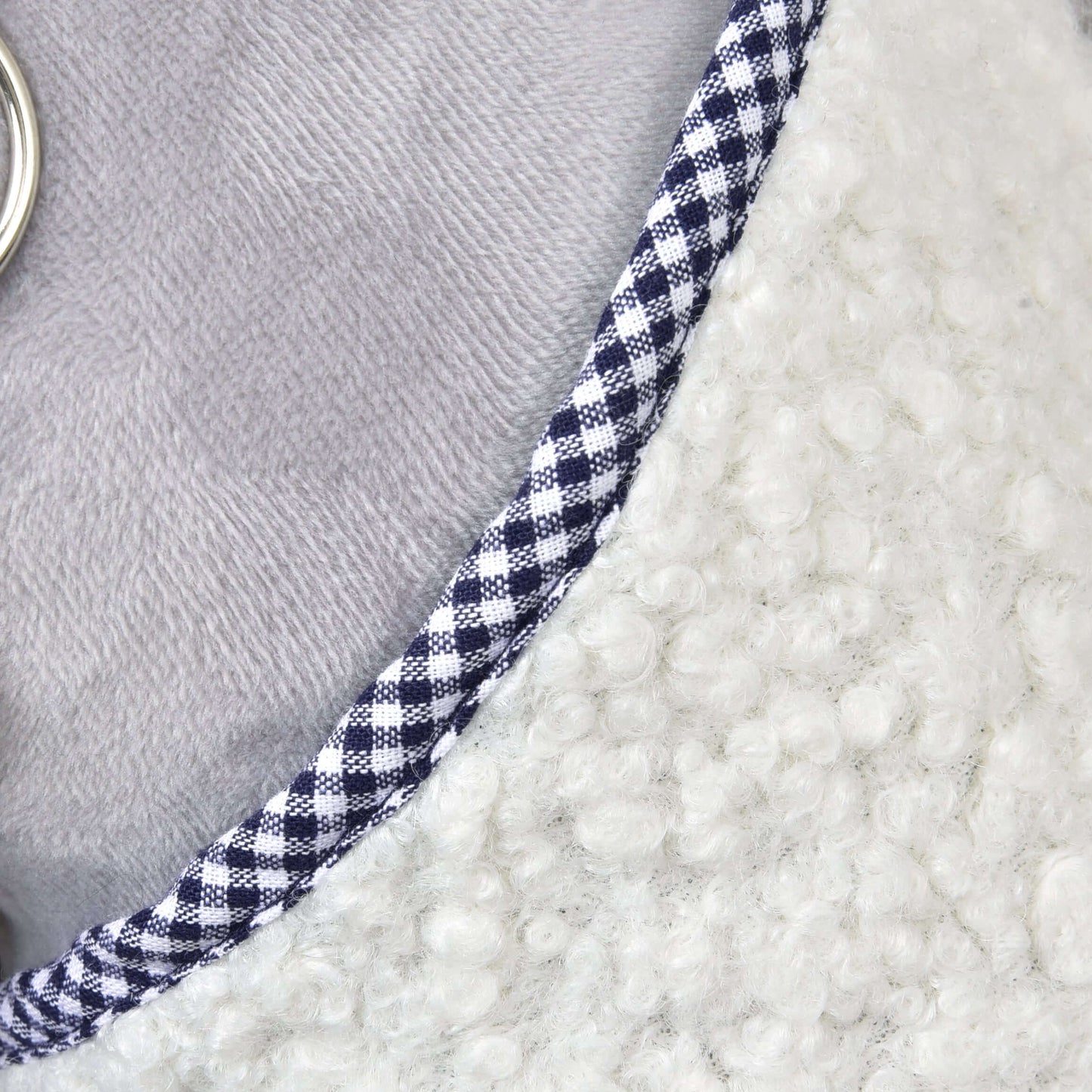 Detail Deky Cube Blue od Hobby Horse LarDen, zvýrazňující bílý texturovaný fleece, modrobílý kostkovaný lem, hladkou světle šedou látku a malý stříbrný kroužek na levém okraji.