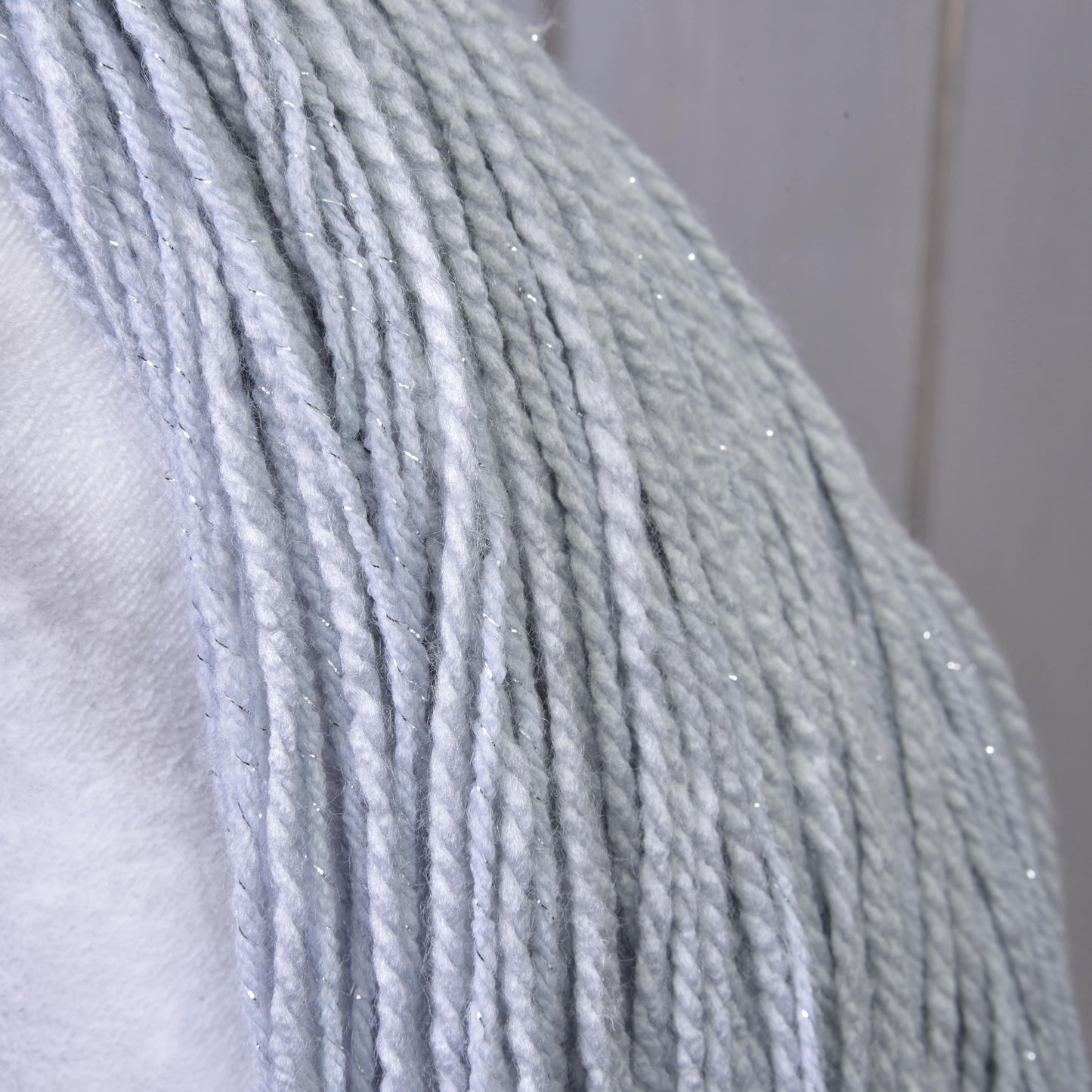 Detail Hobby Horse jednorožec Silver s uzdou a ohlávkou od Hobby Horse LarDen se světle šedou přízí s jemnými stříbrnými třpytkami, rozloženou na bílém povrchu pro kouzelný třpyt inspirovaný jednorožcem.