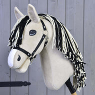 Hobby Horse Aurora s černou ohlávkou od Hobby Horse LarDen, s béžovou plyšovou hlavou, černo-bílou přízovou hřívou a na dřevěné tyči, před šedou dřevěnou stěnou.