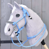 Provazový set Malibu na plyšovém Hobby Horse se šedou srstí, bílou hřívou a lysinou; modrá provazová ohlávka s černobílými akcenty a ladící otěže, na dřevěné tyči před šedým dřevěným pozadím.