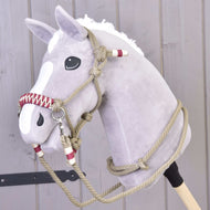 Šedý plyšový Hobby Horse s bílou hřívou a lysinou, který má na sobě provazový set Eleganza od Hobby Horse LarDen, stojí před světlou dřevěnou stěnou.