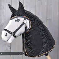 Realistický Hobby Horse s bílou hlavou, černou hřívou a černou uzdečkou stojí na pozadí světlých dřevěných panelů a má na sobě Hobby Horse LarDen Pláštěnka Luxury.