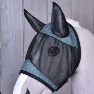 Detail koně s maskou proti hmyzu de Luxe Turquoise od Hobby Horse LarDen, černou síťovanou omyvatelnou maskou s tyrkysovým lemováním, která pro ochranu zakrývá oči a uši. V pozadí je dřevěné obložení.