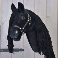 Hobby Horse Maximus s černou ohlávkou od Hobby Horse LarDen, plyšový černý fríský Hobby Horse s dlouhou černou hřívou, na dřevěné tyči, zobrazený před světlým dřevěným obložením.