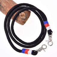 Otěže Emblem CZ od Hobby Horse LarDen, černá pletená šňůra z polypropylenového lana s kovovými karabinami a červenými, modrými a bílými nitěnými akcenty u karabin, stočená kolem dřeva na bílém pozadí.