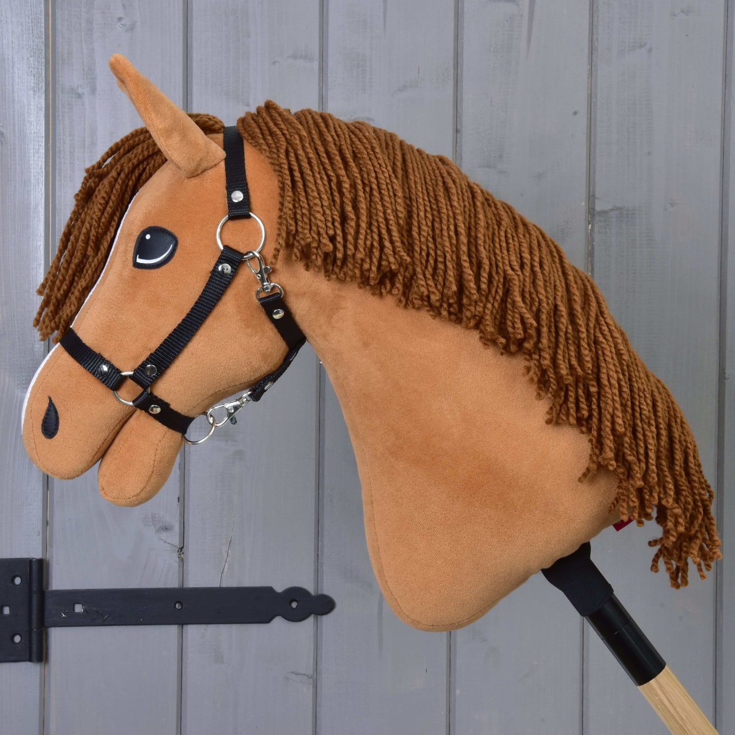 Hobby Horse Wendy s černou ohlávkou od Hobby Horse LarDen má plyšovou hlavu inspirovanou ryzkou klisnou, černou ohlávku a hřívu z příze na dřevěné tyči – ideální pro drezurní nebo parkurovou hru na jakémkoli pozadí.