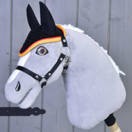Detail šedého Hobby Horse LarDen s uzdečkou a háčkovanou čabrakou Flag pro ochranu proti hmyzu, s výrazným okem, bílou hřívou, černými ušima a čabrakou s oranžovým lemováním, na dřevěném pozadí.