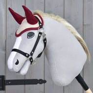 Čabraka Maroon Star od Hobby Horse LarDen na plyšovém hobby horse s bílým tělem, černou uzdečkou a krémovou hřívou, nasazeném na tyči na dřevěném pozadí, pro ochranu proti hmyzu.