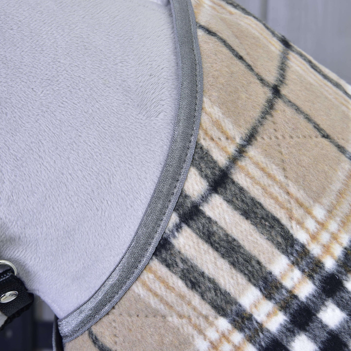 Detail světle šedého psa v Hobby Horse LarDen „Deka Cremo England“, béžovém, černém a bílém kostkovaném kabátku se šedým lemováním a černým páskem se stříbrným kroužkem pro extra ochranu před hmyzem.