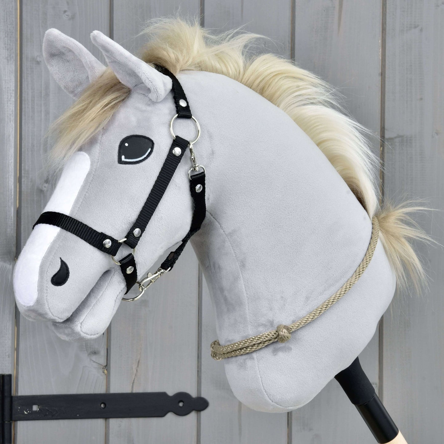 Hobby Horse LarDen Nákrčník Eleganza se šedou plyšovou hlavou, černou uzdečkou a béžovou hřívou na tyči, na pozadí dřevěných prken – ideální pro nácvik ježdění bez uzdečky nebo technik cordero.