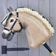 Hobby Horse Ozzy s černou ohlávkou od Hobby Horse LarDen s plyšovým béžovým obličejem, krémovo-černou přízovou hřívou a dřevěnou tyčí, zobrazený na pozadí šedého dřeva.