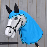 Pláštěnka Sky Blue od Hobby Horse LarDen na šedo-bílém Hobby Horse s černými otěžemi a ušima, který má na sobě lesklou kapuci ve stylu pláštěnky v nebesky modré barvě, na dřevěném pozadí.