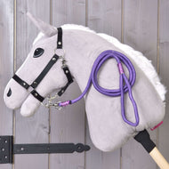 Hobby Horse - vodítko Viola od Hobby Horse LarDen s plyšovým Hobby Horse, bílou hřívou, černou uzdečkou, fialovým provazovým vodítkem a dřevěnou tyčí, zobrazené před světlou dřevěnou stěnou.