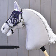 Detail hračky Hobby Horse LarDen se šedým tělem, bílou přízovou hřívou a černou ohlávkou s lila třásněmi, na dřevěném pozadí.